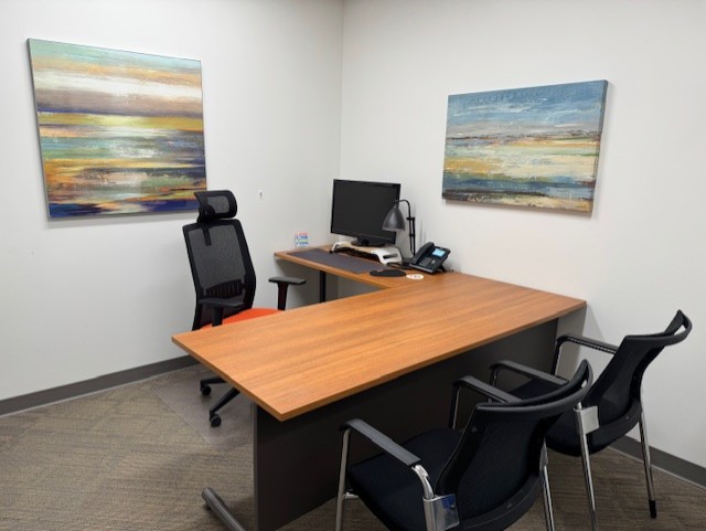 Day Office for several people. Elegant office workspace with computer, chairs, desk, paintings on wall.