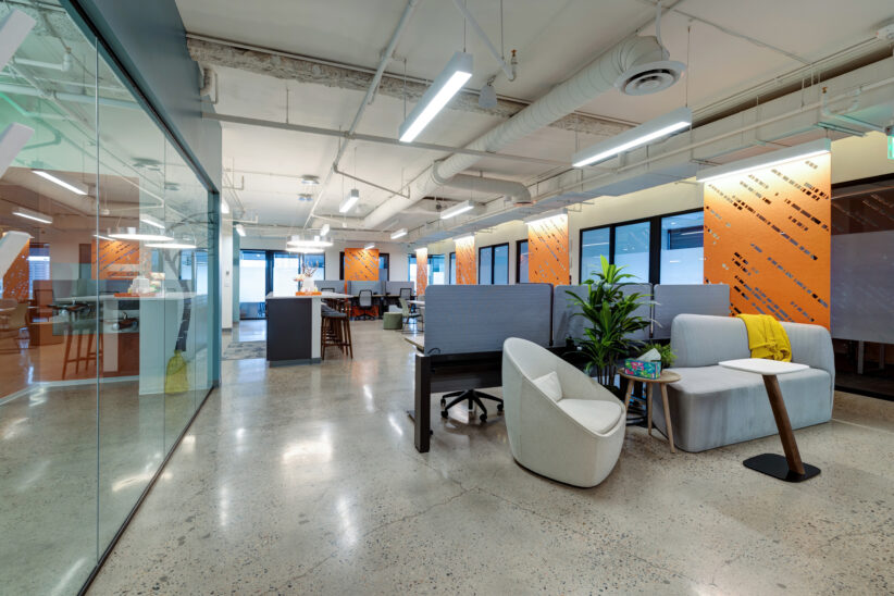 Large open workspace and lounge for coworking with height adjustable standing desks, ergonomic chairs, soft seating with couches and lounge chairs, lots of tables and work areas