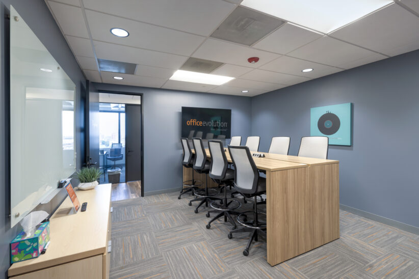 Alternative angle of large conference room with seating for 8, a large TV for display, power built in, and a large glass white board
