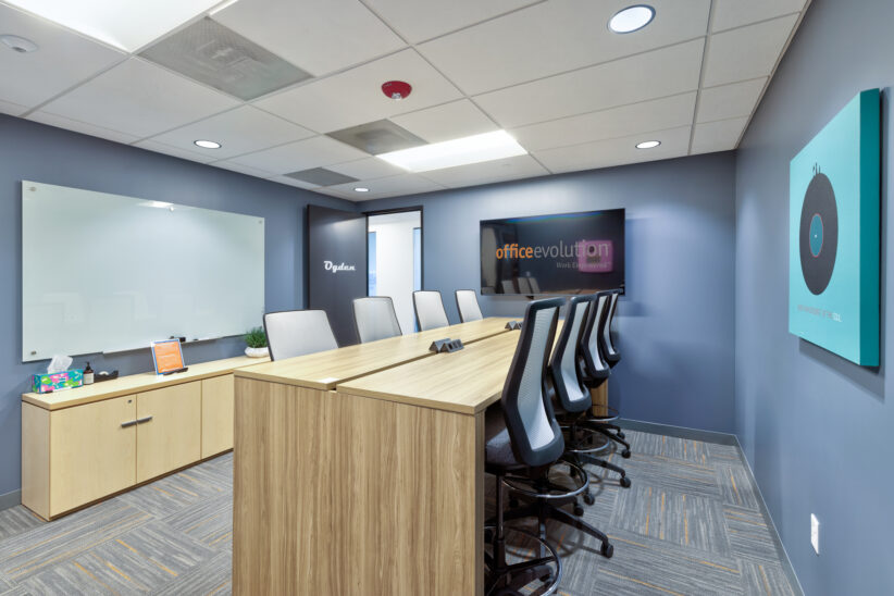 Modern conference room with seating for 8, large TV display and clean glass whiteboard